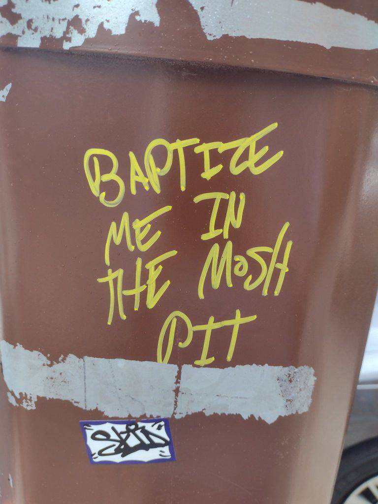 a piece of graffiti that reads: BAPTIZE ME IN THE MOSH PIT